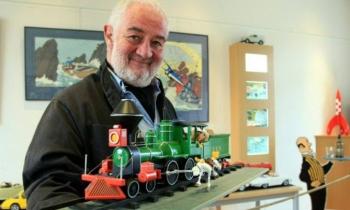 12320 | Michel Aroutcheff - "Après cinq années d'architecture à l'école des Beaux Arts de Paris, Michel Aroutcheff crée et fait réaliser pour et par différentes sociétés des meubles et des jouets dont les voitures en bois laqué. En 1986, il fonde sa propre entreprise qui produit et diffuse ses créations ainsi qu'une collection de véhicules et d'objets issus des albums de Tintin, de Spirou, de Gaston Lagaffe et de Blake et Mortimer. Michel Aroutcheff crée et fabrique ces modèles en bois laqué dans son atelier situé dans un village de Haute Savoie entre Annecy et Genève. La sobriété des lignes, la qualité de la laque et le choix des couleurs en font des objets d'une finition remarquable. Parmi ses objets de collection, la célèbre fusée de Tintin à damier rouge et blanc reste la figure emblématique des premières créations."